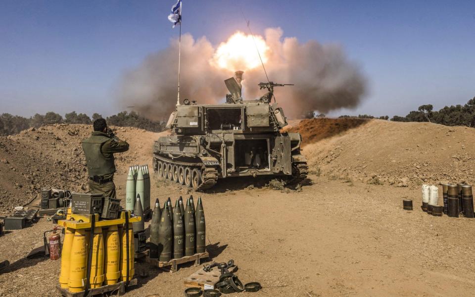 An Israeli army soldier covers his ears as a self-propelled artillery howitzer fires rounds from a position near the border with the Gaza Strip