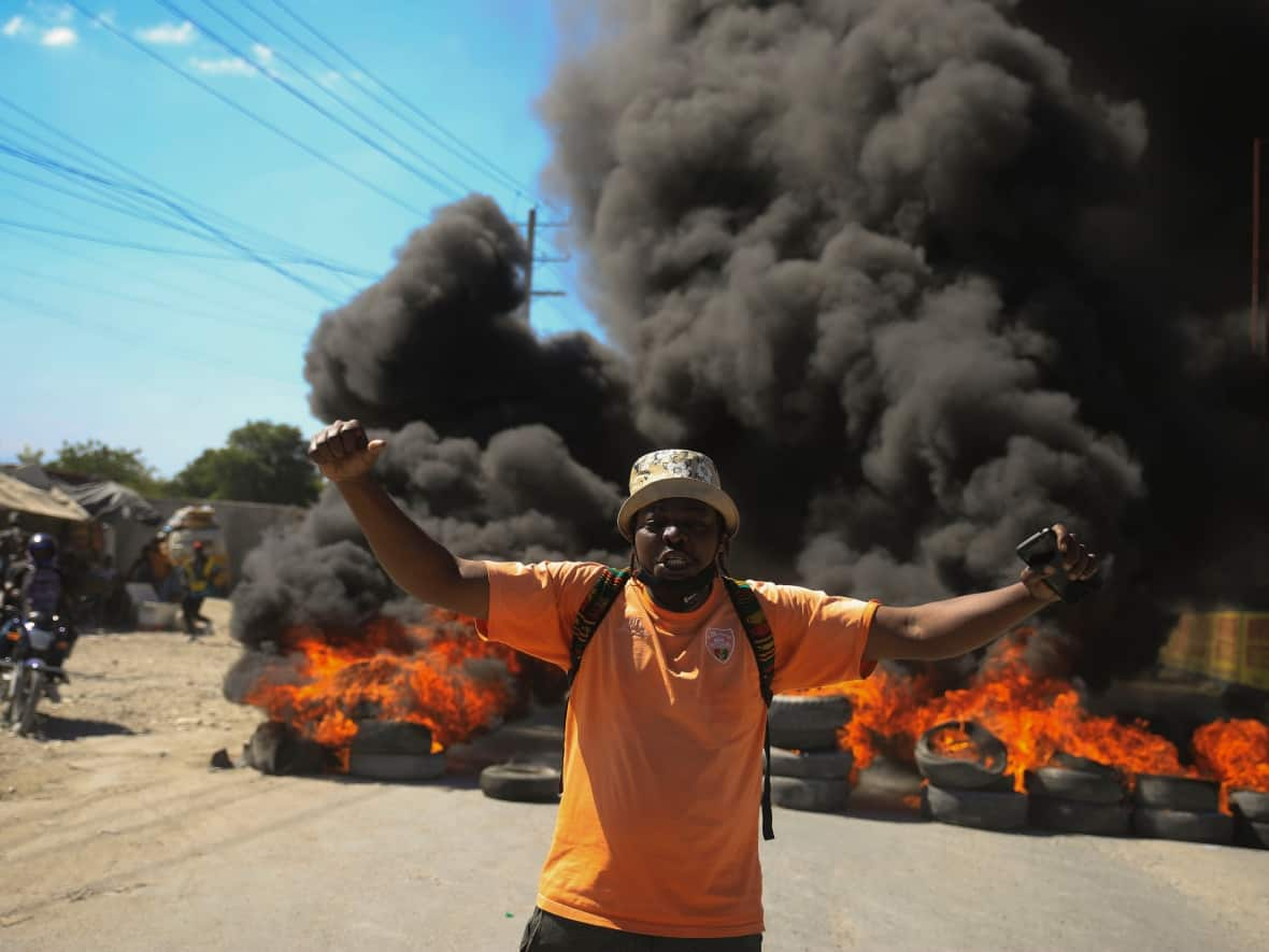 A protester shouts anti-government slogans by a burning barricade set up by members of the police to protest bad police governance in Port-au-Prince, Haiti, on Jan. 26. A wave of grisly killings of police officers by gangs has spurred outrage among Haitians. (Odelyn Joseph/The Associated Press - image credit)