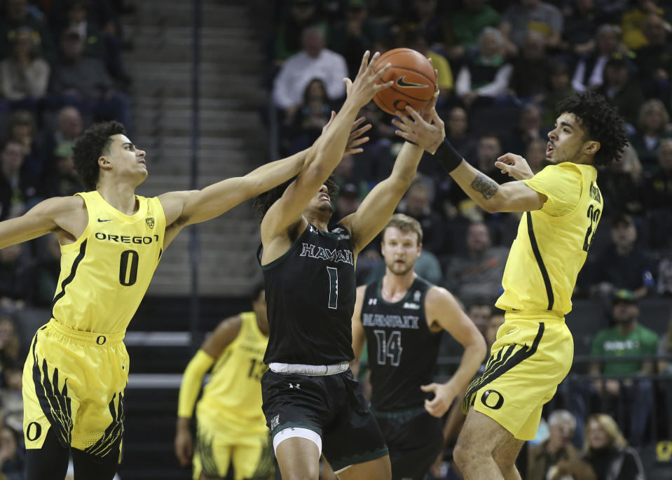 Oregon's Will Richardson, left, and Addison Patterson, right, work against Hawaii's Drew Buggs, center, for the ball during the first half of an NCAA college basketball game in Eugene, Ore., Saturday, Dec. 7, 2019. (AP Photo/Chris Pietsch)