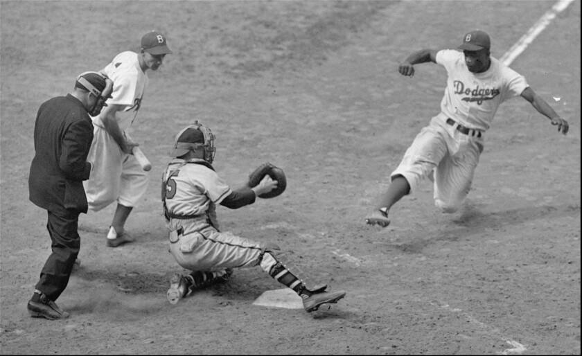 FILE –– Brooklyn Dodgers Jackie Robinson, steals home plate as Boston Braves' catcher Bill Salkeld is thrown off–balance on pitcher Bill Voiselle's throw to the plate during the fifth inning at Ebbets Field in New York August 22, 1948. The umpire is Jocko Conlan. (AP Photo/File)