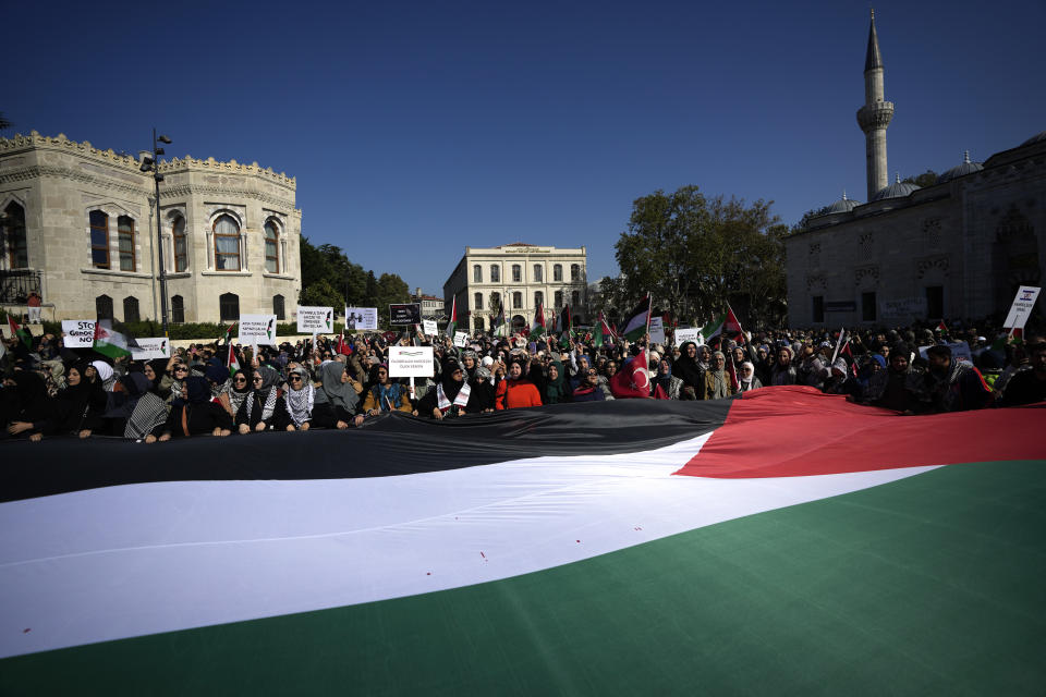 Protesters chant slogans while holding a giant Palestinian flag during a protest to show their solidarity with the Palestinians, in Istanbul, Turkey. Friday, Oct. 20, 2023. (AP Photo/Khalil Hamra)