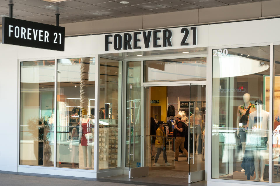 The image shows the entrance of a Forever 21 retail store in a shopping mall. The storefront displays clothing and mannequins through the glass windows