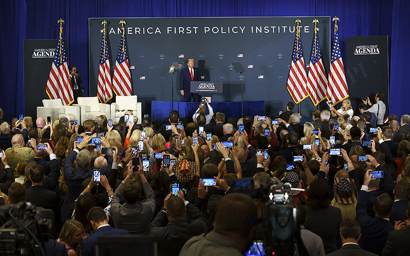 Attendees photograph former President Trump as he arrives on stage to give a keynote address during the America First Policy Institute summit in Washington, D.C., on July 26. <em>Greg Nash</em>