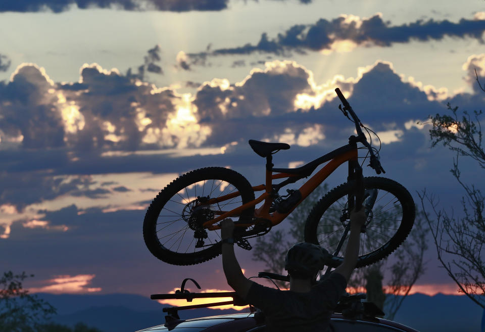 A man lifts his bike off his roof rack to beat the heat with an early start at dawn, Tuesday, July 24, 2018 in Phoenix. Much of Arizona and parts of California, Arizona and Utah are under an excessive heat watch during a week that forecasters say could prove to be the hottest of the year. (AP Photo/Matt York)