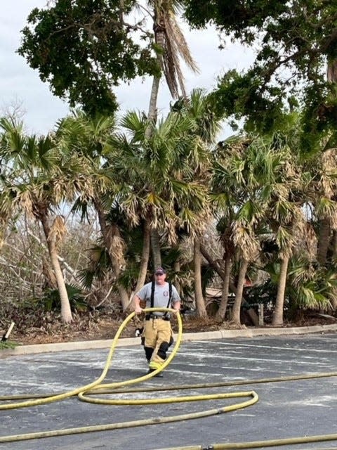 A Sanibel Fire Rescue District fireman positions a hose in the parking lot at The Dunes Golf and Tennis Club on Friday, Nov. 18, 2022. A fire erupted in the club's fleet of golf carts, causing thick, black smoke that could be seen miles away.