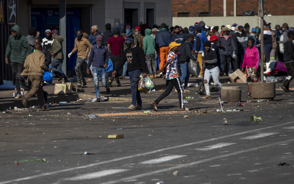 Looters carry items at Letsoho Shopping Centre in Katlehong, east of Johannesburg, South Africa, Monday, July 12, 2021. Police say six people are dead and more than 200 have been arrested amid escalating violence during rioting that broke out following the imprisonment of South Africa's former President Jacob Zuma. (AP Photo/Themba Hadebe)