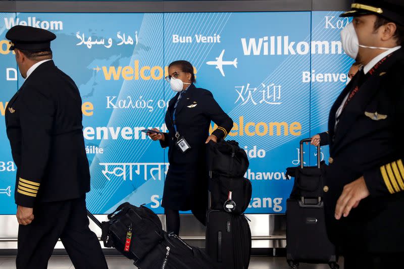 FILE PHOTO: Members of a flight crew wear face masks as they arrive at John F. Kennedy International Airport in New York