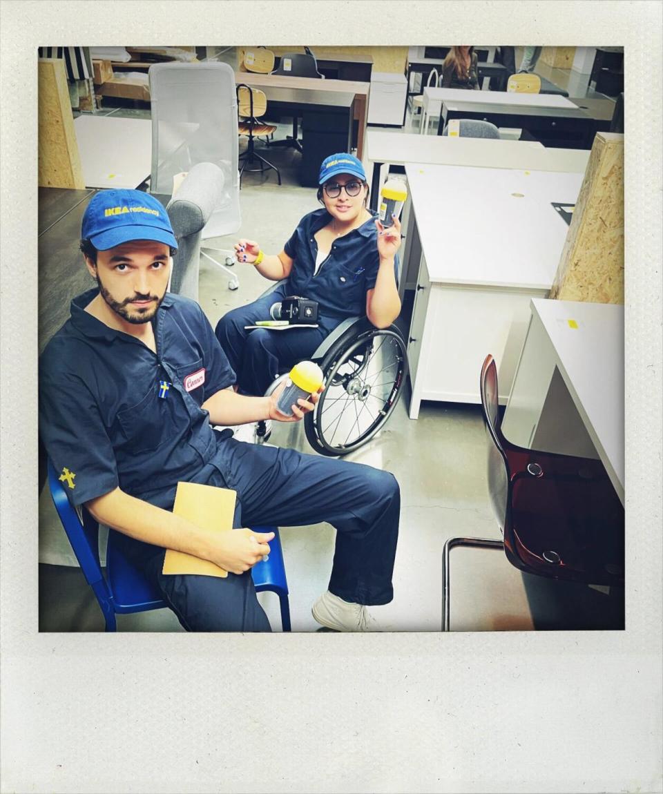 Two people in blue coveralls and blue baseball hats pose for a portrait at Ikea.