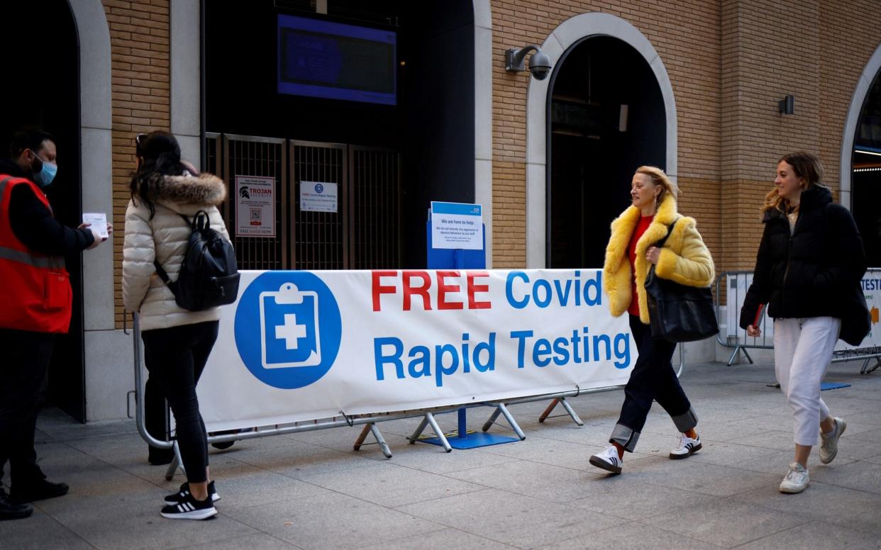 Pedestrians walk past a sign directing people to a rapid lateral flow Covid-19 testing centre at London Bridge - AFP