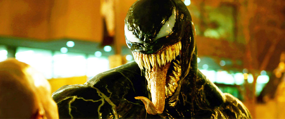 Venom, an alien symbiote with a large mouth full of sharp teeth and a long tongue, faces an unseen character. His expression appears threatening