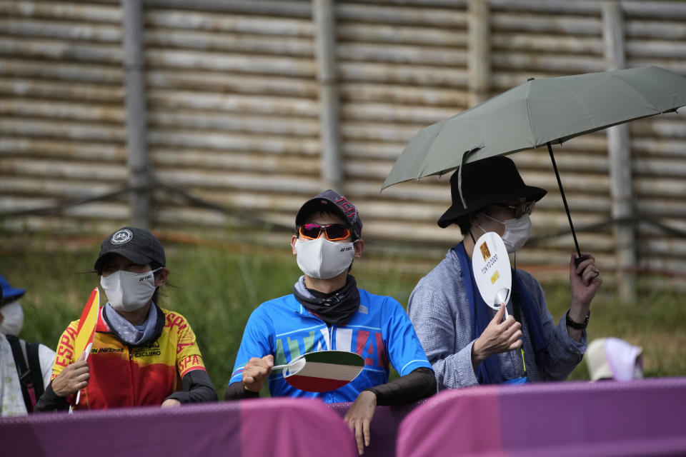 Supporters use fans to beat the heat at the men's cross country mountain biking at the 2020 Summer Olympics, Monday, July 26, 2021, in Izu, Japan. (AP Photo/Christophe Ena)
