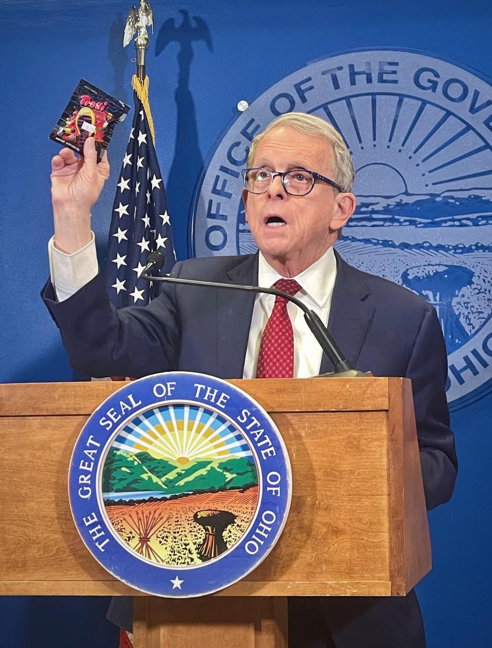 Gov. Mike DeWine holds up a delta-8 product as he calls on Ohio lawmakers to regulate the compound during a news conference on Wednesday.