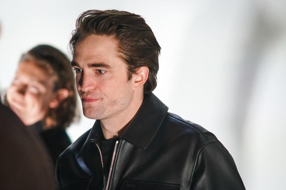 wearing a cool leather jacket with his slicked-back hair, Rob mingles at Paris Fashion Week