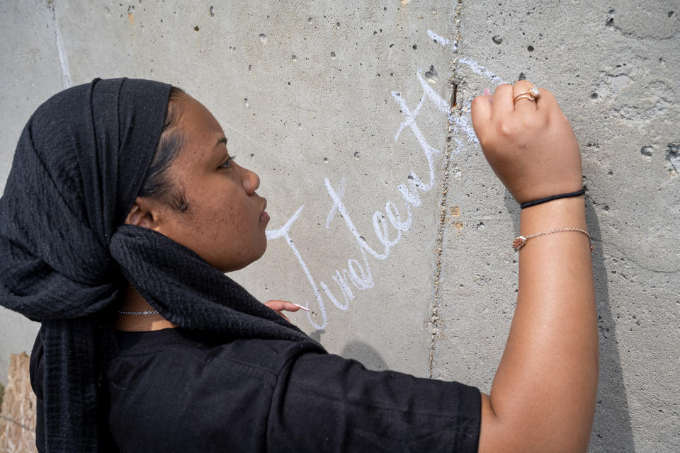 A young person writes Juneteenth on a wall in chalk in Louisville, Kentucky. (Jon Cherry / Getty Images)
