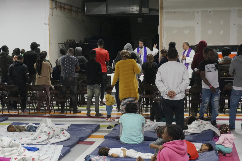 The Rev. Louie Hotop, a Jesuit priest, center, celebrates Mass for migrants in the large room where they rest and sleep after being admitted to the United States at the Humanitarian Respite Center in McAllen, Texas, on Dec. 15, 2022. Dozens of migrants are allowed to enter the United States daily here on humanitarian parole or other mechanisms to seek asylum, and thousands are expected to come if asylum policies change next week. (AP Photo/Giovanna Dell'Orto)