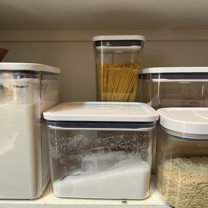 five of the bins in varying sizes with pantry goods stored inside.