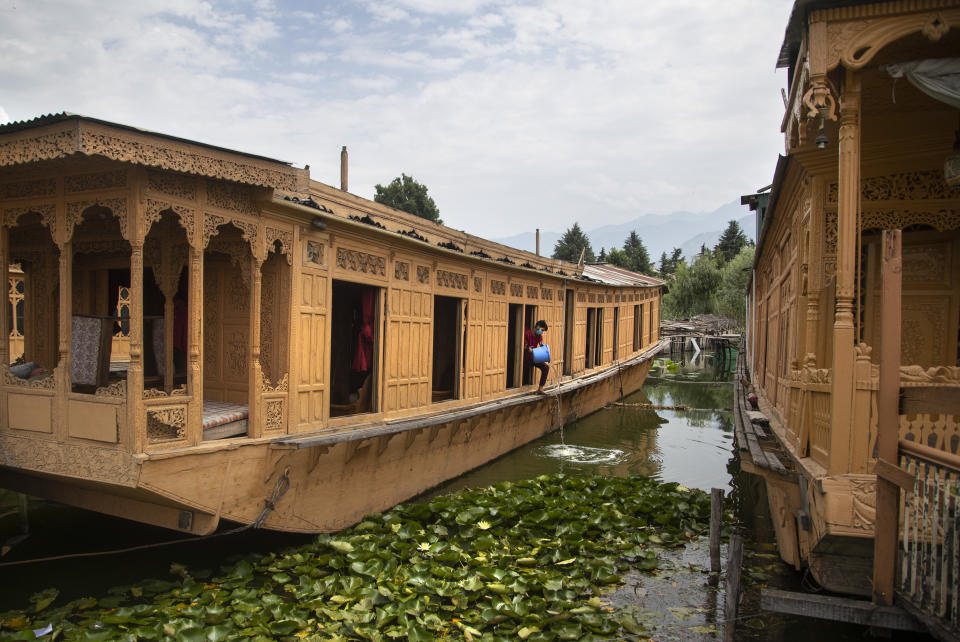 Kashmiri man Illiyas Ahamad cleans an unoccupied houseboat at Nigeen Lake during lockdown to stop the spread of the coronavirus in Srinagar, Indian controlled Kashmir, July 16, 2020. Indian-controlled Kashmir's economy is yet to recover from a colossal loss a year after New Delhi scrapped the disputed region's autonomous status and divided it into two federally governed territories. (AP Photo/Mukhtar Khan)