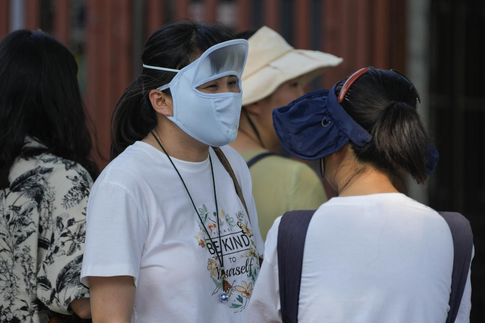 Women wearing face cover and hats chat during an unseasonably hot day in Beijing, Sunday, June 16, 2024. China is being buffeted by two weather extremes, with heavy rain and flooding in parts of the south and a heat wave and potential drought in the north. (AP Photo/Andy Wong)