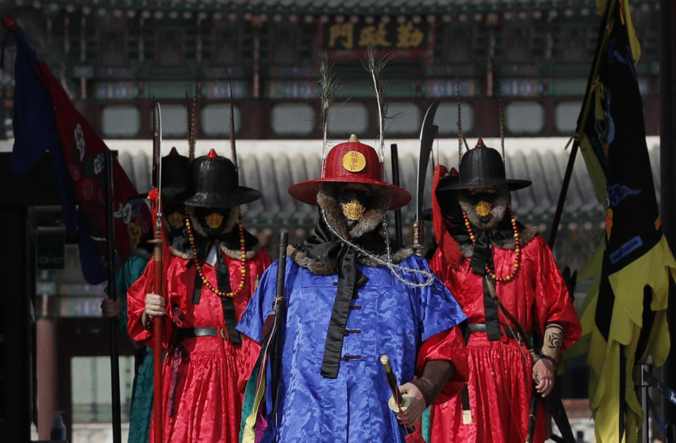 Funcionarios vestidos con uniformes de guardas tradicionales y mascarillas, pasean por el Palacio Gyeongbok, el principal palacio de la dinastía Joseon y uno de los monumentos más importantes de Seúl, Corea del Sur, el 29 de febrero de 2020. (AP Foto/Lee Jin-man)