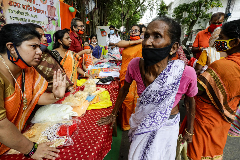 Volunteers of an organization distribute gifts to economically underprivileged people ahead of Durga Puja, the biggest festival of the region, in Kolkata, India, Wednesday, Oct. 21, 2020. Health officials have warned about the potential for the coronavirus to spread during the upcoming religious festival season, which is marked by huge gatherings in temples and shopping districts. Durga Puja, the biggest festival in the region, will be celebrated from Oct. 22-26. (AP Photo/Bikas Das)