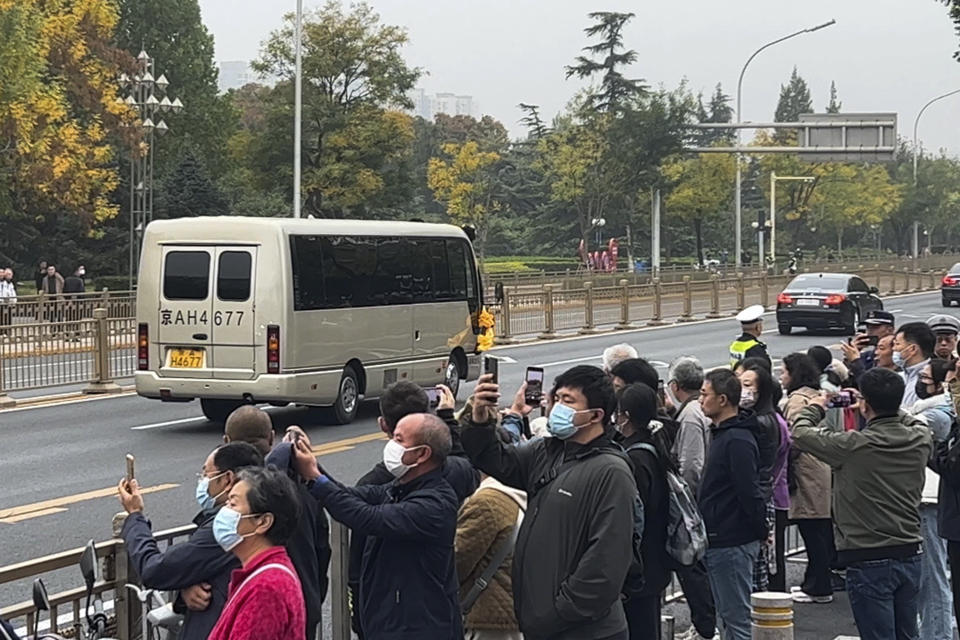 Some people use smartphones to film a vehicle with flowers which is believed to be carrying the body of former Premier Li Keqiang as the convoy heads to the Babaoshan Revolutionary Cemetery in Beijing Thursday, Nov. 2, 2023. Hundreds, possibly thousands, of people gathered near a state funeral home Thursday as former Premier Li Keqiang was being put to rest. (AP Photo)