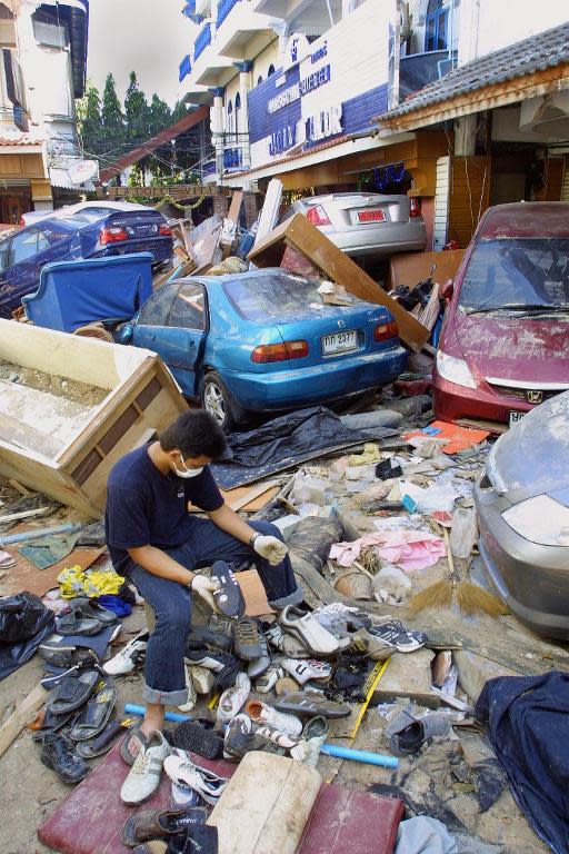 A Thai man tries to salvage items from his destroyed shoe shop, surrounded by a pile of cars along Patong beach in Phuket, southern Thailand a few days after the tsunami