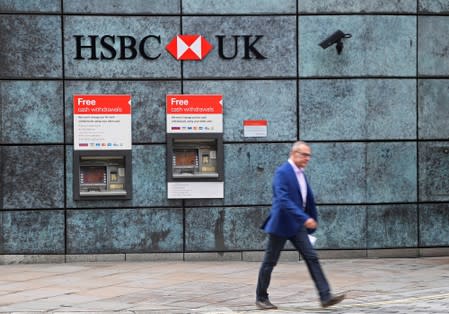 FILE PHOTO: A worker walks past a branch of HSBC bank in the City of London financial district in London