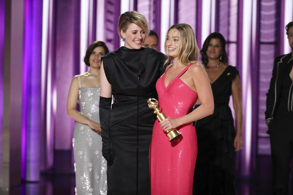 En esta imagen proporcionada por CBS, la directora Greta Gerwig, izquierda, y la actriz Margot Robbie reciben el premio al logro cinematográfico y de taquilla por “Barbie” en la 81a edición de los Globos de Oro el domingo 7 de enero de 2024, en el Hotel Beverly Hilton en Beverly Hills, California. (Sonja Flemming/CBS via AP)