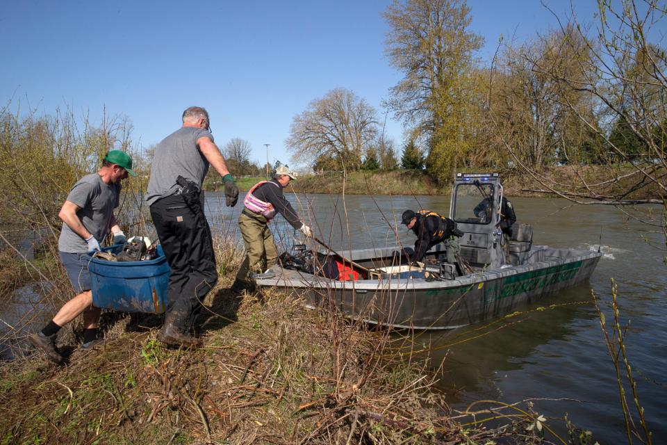 Volunteers load garbage onto a Lane Country Sheriff's jet boat from an island in the Willamette River.