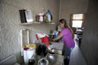 Myriam Roncancio, who is living with her parents after breaking up with her husband of 10 years, wipes down the kitchen counter during a nationwide stay-at-home order to prevent the spread of the new coronavirus, in the Soacha borough of Bogota, Colombia, Tuesday, July 28, 2020. Now the 35-year-old shares a room with her two children in her parents’ apartment and gets out only twice a week to buy groceries. “It’s like a ghost town,” she said. “I can’t get used to it.” (AP Photo/Fernando Vergara)