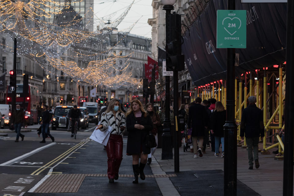 Shoppers and commuters walk along Oxford Street ahead of introduction of tougher coronavirus restrictions in the run up to Christmas, on 15 December, 2020 in London, England. From tomorrow, Greater London, as well as parts of Essex and Hertfordshire, will move into Tier 3 coronavirus restrictions resulting in closing of pubs, bars, restaurants, hotels and indoor entertainment venues such as theatres and cinemas, as the infection rates are well above the national average and continue to rise. (Photo by WIktor Szymanowicz/NurPhoto via Getty Images)