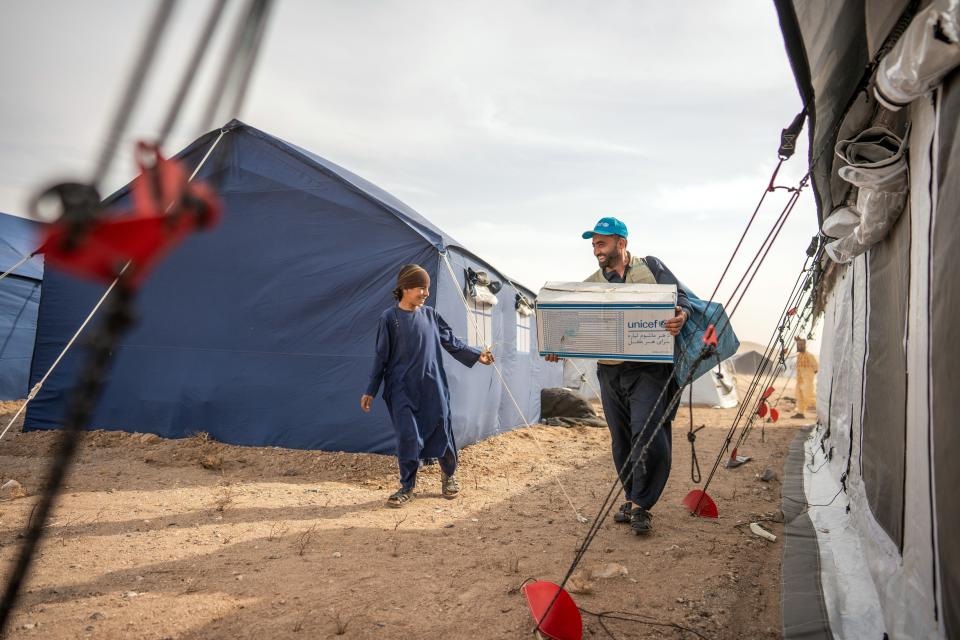 Fahim Radmanish, UNICEF Afghanistan Emergency Officer, carries winter clothing and household supplies (including cooking equipment) for 12-year-old Ahmad in Koshkak village, Zinda Jan District, western Afghanistan. With more than 3,000 homes destroyed, many families now live in tents and are dependent on humanitarian aid.