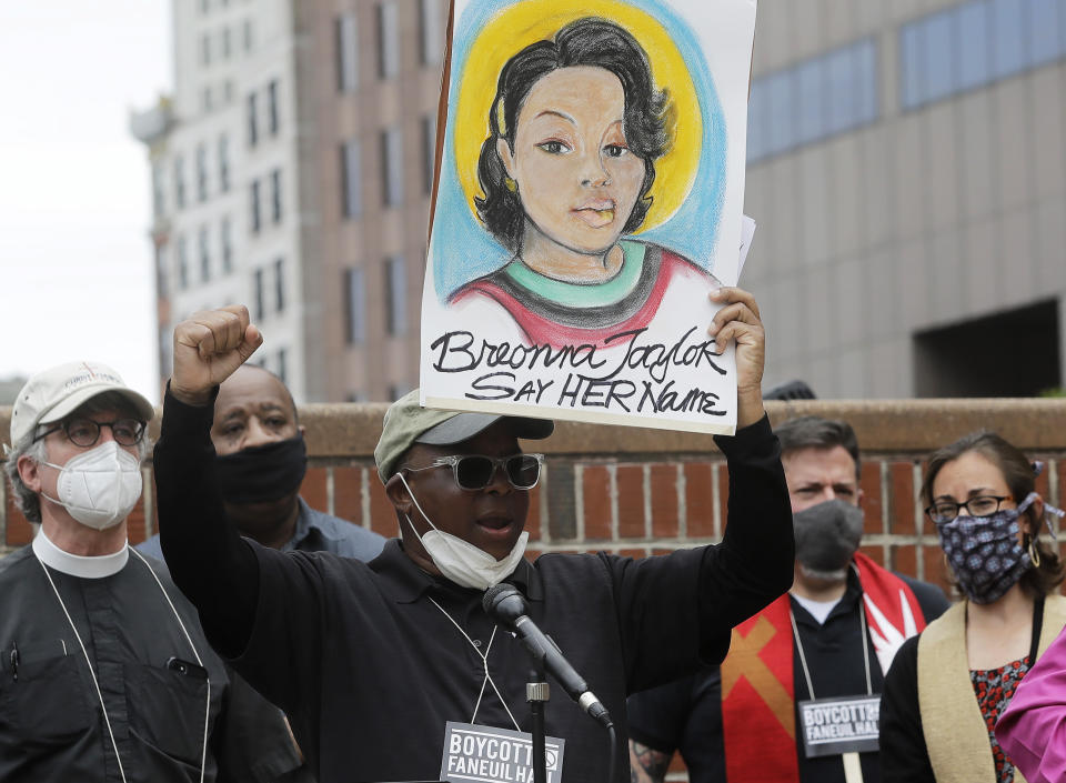 FILE - In this June 9, 2020, file photo, Kevin Peterson, center, founder and executive director of the New Democracy Coalition, displays a placard showing Breonna Taylor as he addresses a rally in Boston. Louisville's mayor says one of three police officers involved in the fatal shooting of Taylor will be fired, Friday, June 19, 2020. Taylor was gunned down by officers who burst into her Louisville home using a no-knock warrant. She was shot eight times by officers conducting a narcotics investigation. No drugs were found at her home. (AP Photo/Steven Senne, File)