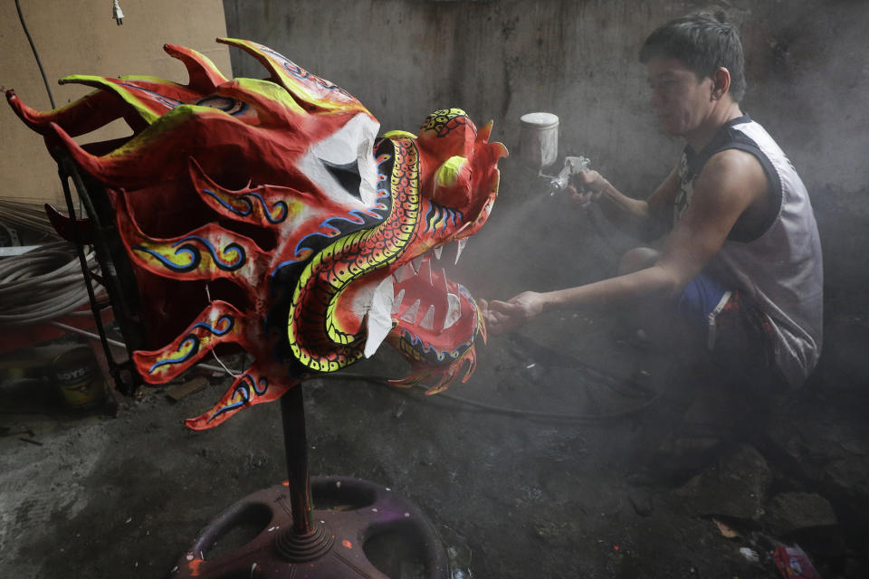 Robert Sicat sprays a protective coating on a Dragon head at a creekside slum at Manila's Chinatown, Binondo Philippines on Feb. 4, 2021. The Dragon and Lion dancers won't be performing this year after the Manila city government banned the dragon dance, street parties, stage shows or any other similar activities during celebrations for Chinese New Year due to COVID-19 restrictions leaving several businesses without income as the country grapples to start vaccination this month. (AP Photo/Aaron Favila)