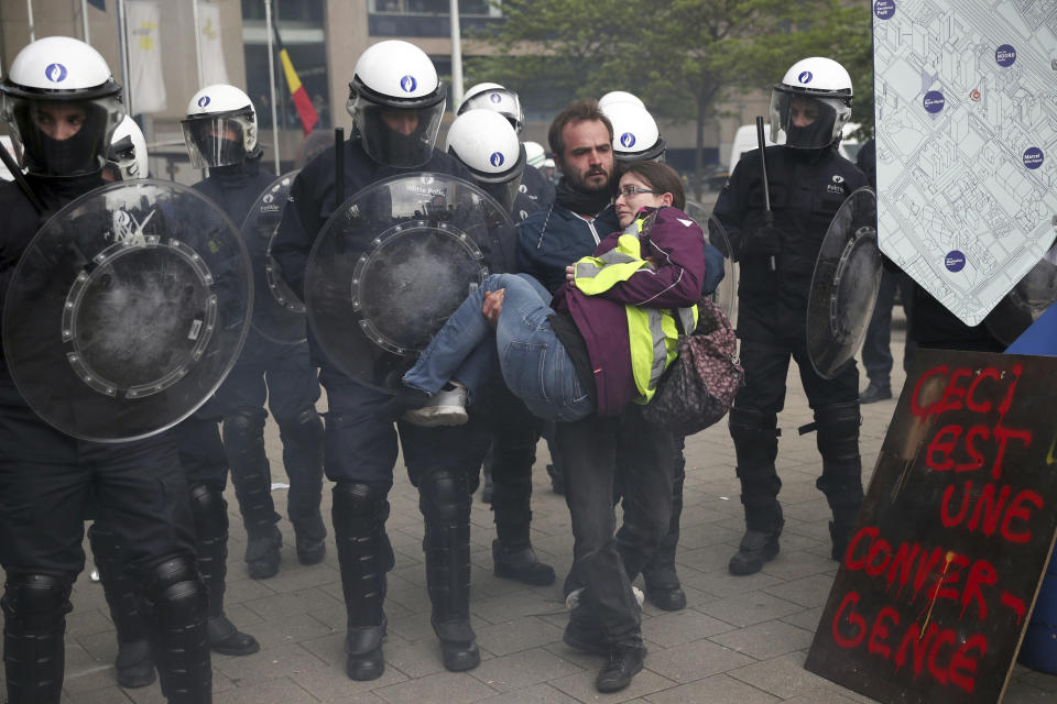 A man carries a yellow vest protestor in front of a police line during a demonstration in Brussels, Sunday, May 26, 2019. The demonstration took place as Belgium took to the polls to elect regional, national and European candidates. Sign reads, this is a coming together. (AP Photo/Francisco Seco)