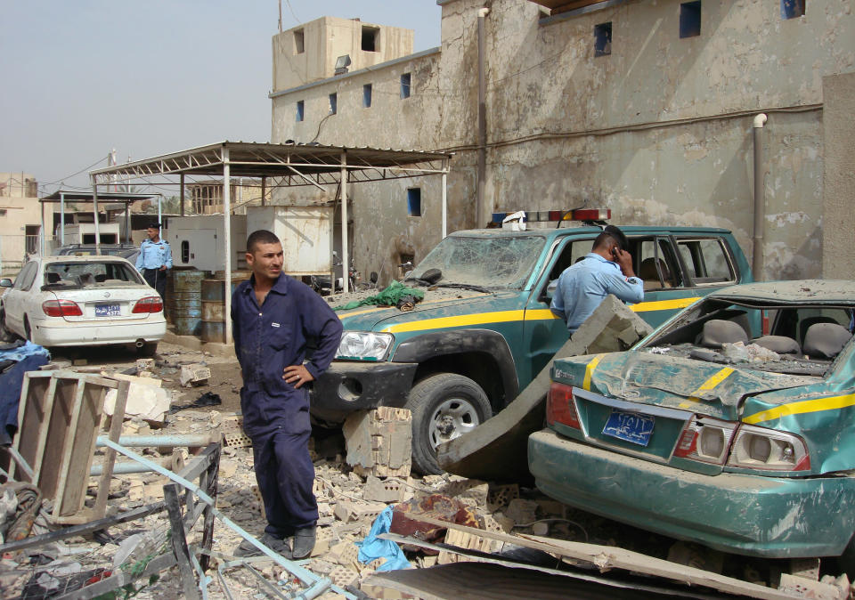 A member of the civil defence (C) and policemen inspect the site of a bomb attack in Hilla, 100 km (60 miles) south of Baghdad May 5, 2011. At least 16 people were killed and 41 wounded on Thursday when a car bomb exploded in Iraq's southern city of Hilla, medical and police sources said, as security forces braced for likely attacks by al Qaeda. A suicide bomber rammed his car into the entrance of a police quarters based in the centre of the mainly Shi'ite city of Hilla during a shift change when many police officers were outside the building, the sources said. REUTERS/Habib