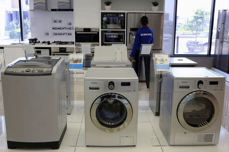 Samsung washing machines are seen as an employee inspects refrigerators at a Samsung display store in Johannesburg, October 3, 2013. REUTERS/Siphiwe Sibeko/File Photo