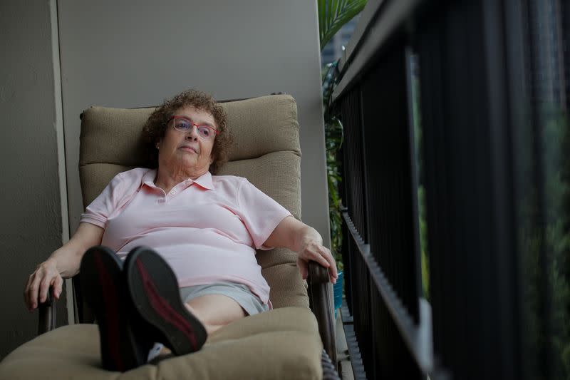 Laura Gross sits down after feeling weak while posing on her balcony in Fort Lee, New Jersey