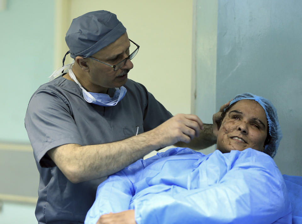 In this Tuesday, Nov. 6, 2018 photo, plastic surgeon Dr. Abbas al-Sahan makes surgical marks around the damaged ear of Saja Ahmed Saleem, before her reconstructive surgery in Baghdad, Iraq. Saleem lost both eyes, right arm and ear and suffered disfigurement in a bomb explosion in 2007 in northern Iraq. Those whom treatment not available at state-run hospitals and can’t afford treatment at private clinics rely on social media to make appeals that grab attention of some surgeons to help them regain a chance at life. (AP Photo/Hadi Mizban)