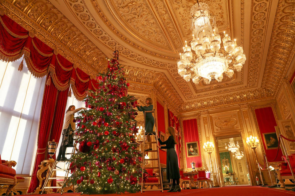 Royal Collection Trust members of staff put the finishing touches to a 15ft Christmas tree in the Crimson Drawing Room at Windsor Castle, Berkshire. (Photo by Steve Parsons/PA Images via Getty Images)