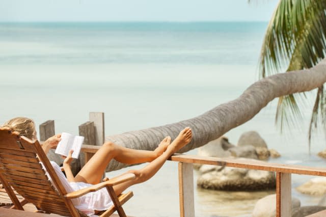 Young woman reading a book while relaxing on tropical island