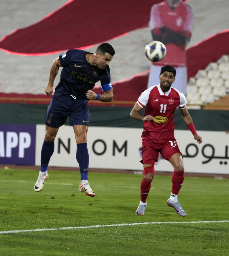 Al Nassr's Cristiano Ronaldo, left, heads the ball watched by Iran's Persepolis Danial Esmaeilifar during their AFC Champions League soccer match at the Azadi Stadium in Tehran, Iran, Tuesday, Sept. 19, 2023. (AP Photo/Vahid Salemi)