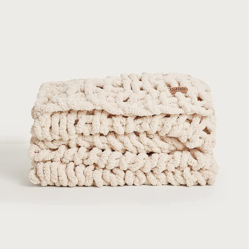 cream colored braided throw blanket against white background