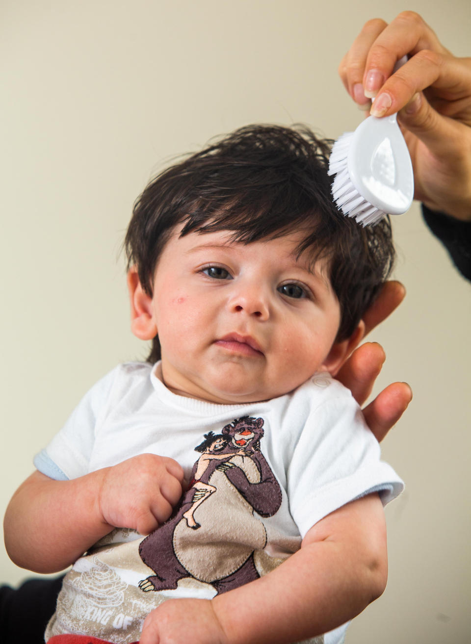 Oscar, pictured at three months old, getting his long locks brushed. [Photo: SWNS]