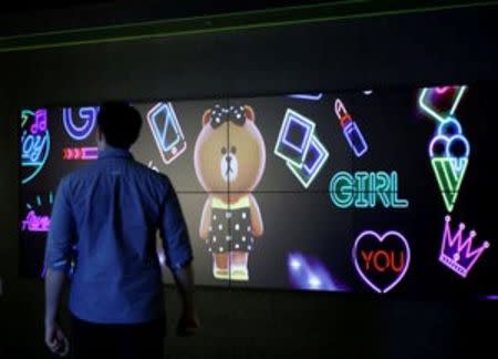 A man walks a screen showing Line character at the Line Corp's headquarters in Tokyo, Japan June 2, 2016. REUTERS/Toru Hanai/File Photo