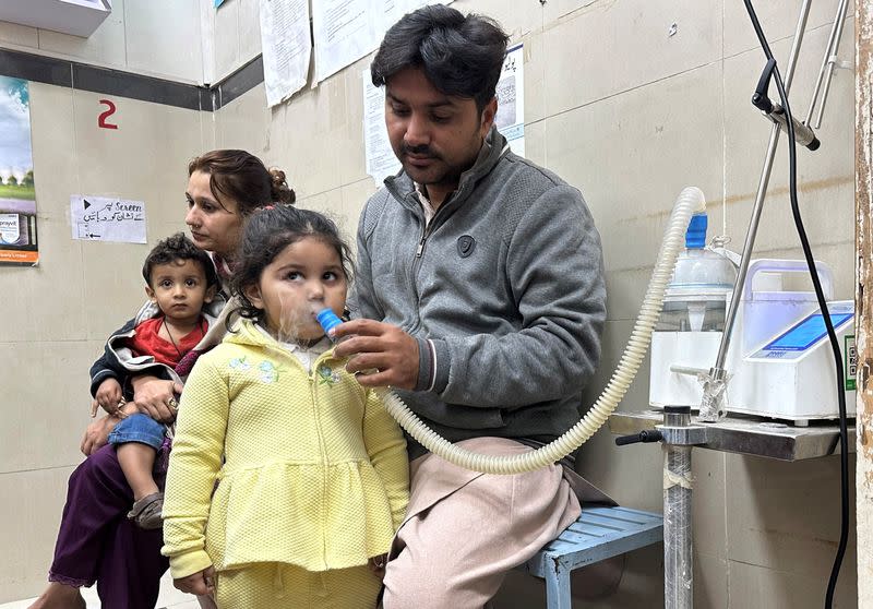 Mohamad Qadeer holds up a nebulizer device to the face of his daughter Rameen at Sir Ganga Ram hospital in Lahore