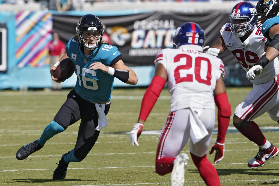 Jacksonville Jaguars quarterback Trevor Lawrence (16) runs towards New York Giants safety Julian Love (20) during the first half of an NFL football game Sunday, Oct. 23, 2022, in Jacksonville, Fla. (AP Photo/John Raoux)