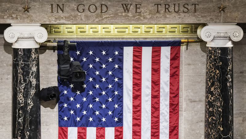 FILE - “In God We Trust” is engraved in stone above a U.S. flag in the House of Representatives chamber at the Capitol in Washington on Tuesday, March 1, 2022. 