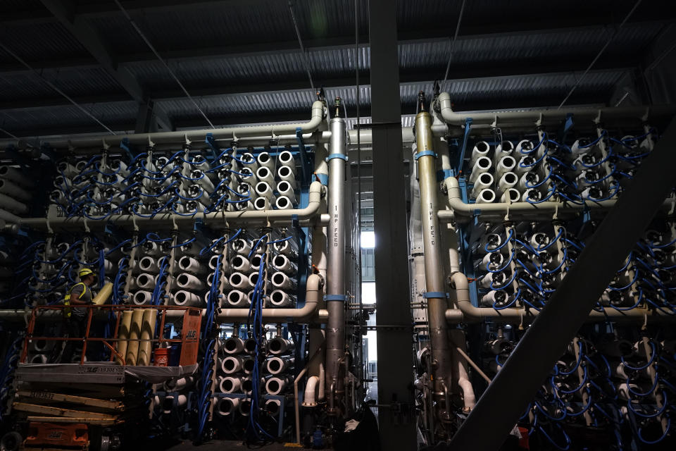 A man performs maintenance work in the reverse osmosis building at the Carlsbad Desalination plant Thursday, May 26, 2022, in Carlsbad, Calif.The facility is the Western hemisphere's largest desalination plant, which removes salt and impurities from ocean water. (AP Photo/Gregory Bull)