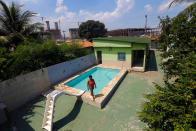 <p>Marcia Lemos, 57, walks by a pool in her house, with cranes and construction work for the Rio 2016 Olympic Park seen in the background, at the Vila Autodromo slum in Rio de Janeiro, Brazil, January 28, 2015. (REUTERS/Ricardo Moraes)</p>